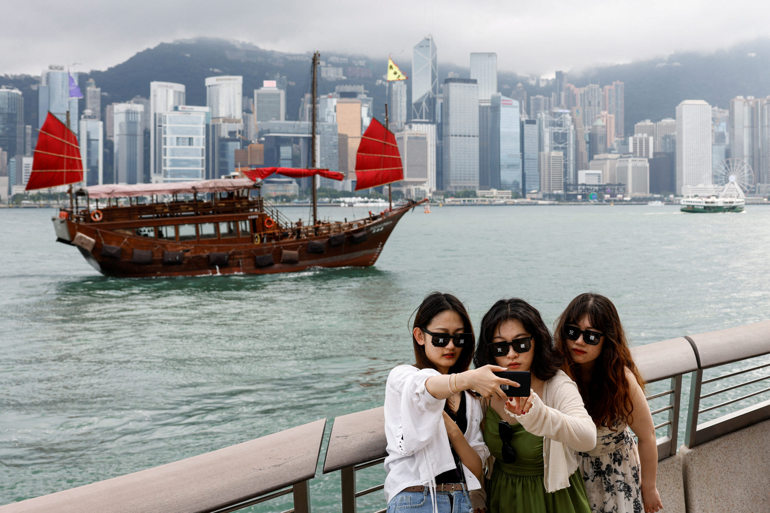 Anglers take photos in front of Victoria Harbour, in Tsim Sha Tsui, in Hong Kong.